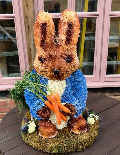 Peter Rabbit Funeral Tribute - A charming Peter Rabbit-inspired floral tribute, complete with carrots and standing approximately 2ft high for a unique and heartfelt farewell.